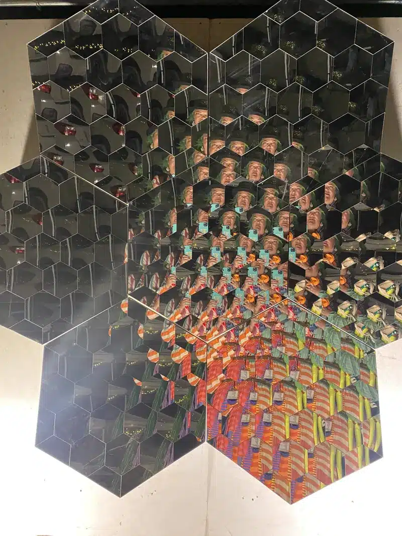 Hexagonal mirrored panels reflecting a kaleidoscope of repeating colorful patterns.