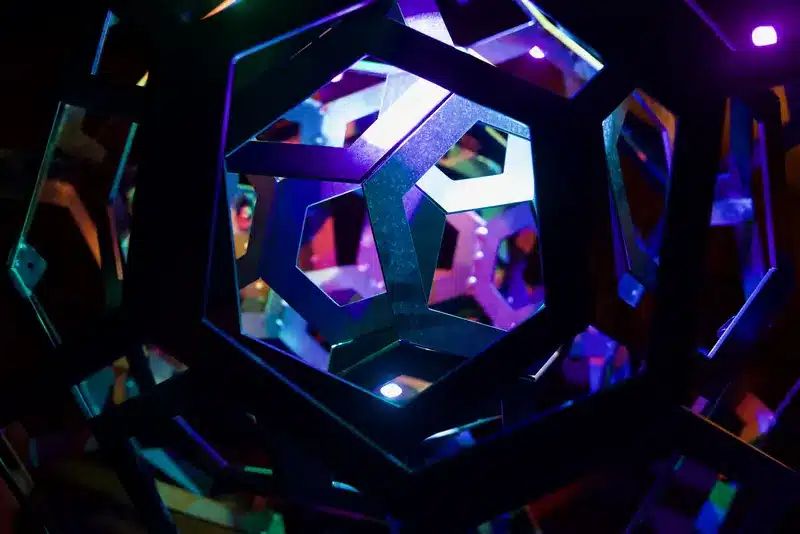 Close-up inside the cut-steel polyhedral sphere, its geometric openings glowing blue and purple.